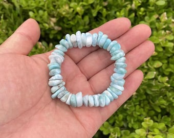 Könnte beinhalten: Ein hellblaues Edelstein-Armband aus kleinen, unregelmäßig geformten Perlen. Das Armband besteht aus natürlichen Steinen und ist eine beliebte Wahl für diejenigen, die gerne Schmuck mit einem natürlichen Look tragen.