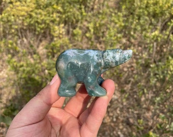 Puede incluir: Figurita de oso tallada en piedra de color verde, blanco y marrón.