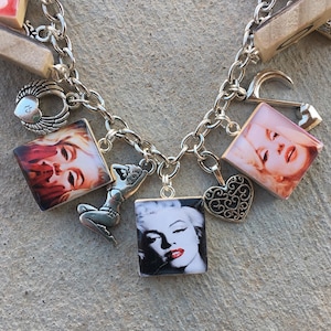 May include: A silver charm bracelet with various charms, including a heart, a winged heart, a pin-up girl, a woman's face, and a silver figure of a woman.