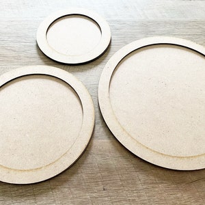 May include: Three unfinished wooden round trays of different sizes. The trays have a raised edge and are perfect for crafting projects.