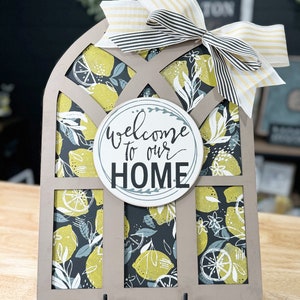 May include: A wooden welcome sign with a lemon pattern and a black and white striped bow. The sign says "Welcome to our Home".