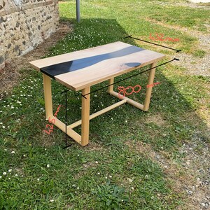 Op de afbeelding: Een houten tafel met een zwart epoxy rivierontwerp. De tafel is 76 cm breed en 122 cm lang.
