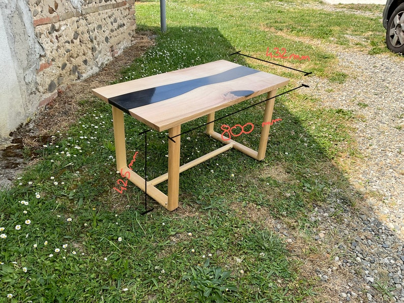 Op de afbeelding: Een houten tafel met een zwart epoxy rivierontwerp. De tafel is 76 cm breed en 122 cm lang.