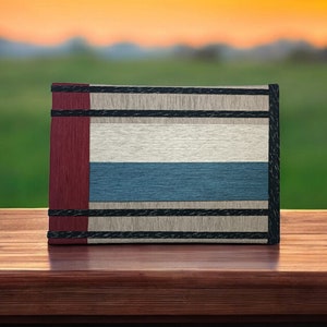 May include: A book with a red, white, and blue striped cover. The book is sitting on a wooden surface.