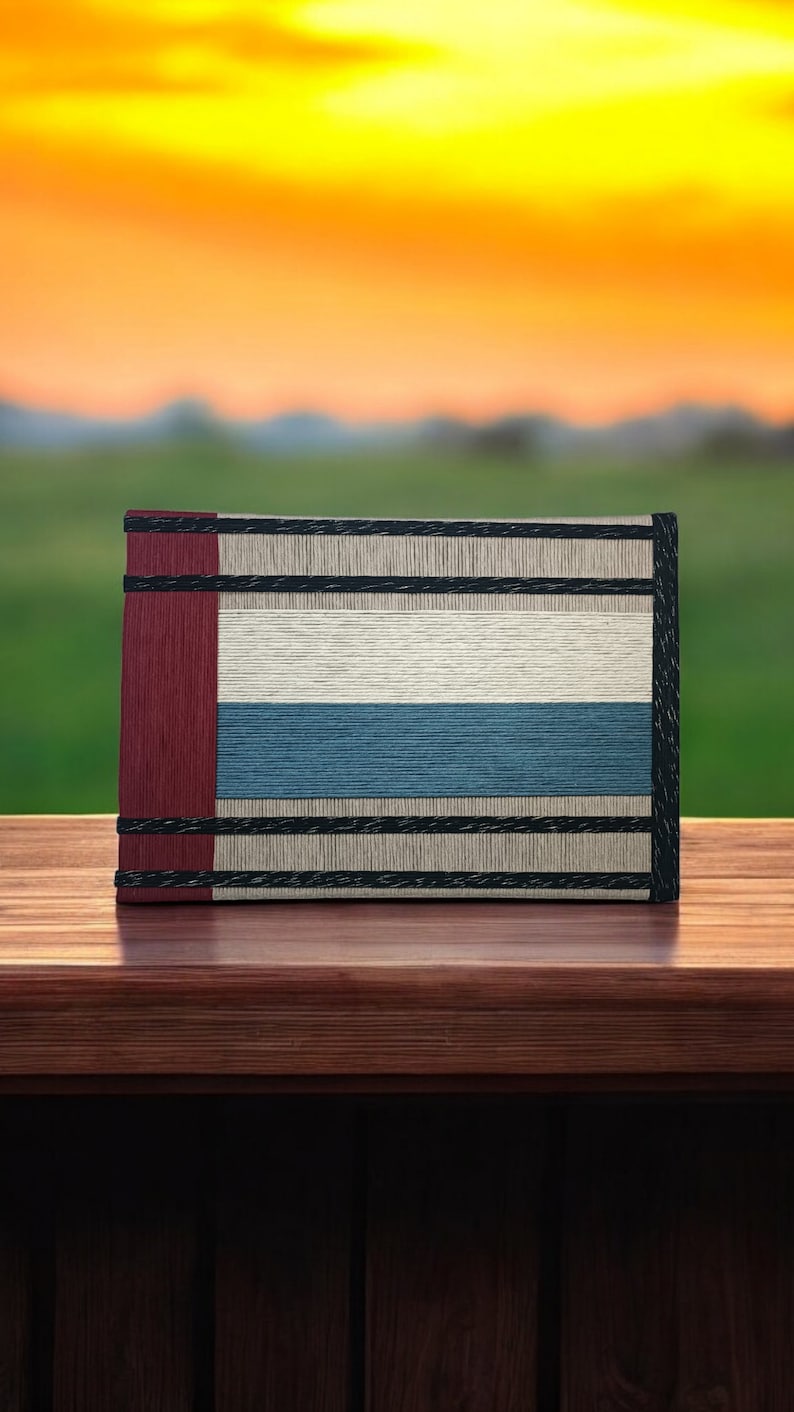May include: A book with a red, white, and blue striped cover. The book is sitting on a wooden surface.
