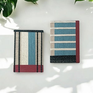 May include: Two decorative rectangular boxes with a striped pattern in shades of blue, white, black, and red. The boxes are on a white background.