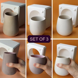 May include: A collection of three ceramic vases in shades of beige, off-white, and mauve, with a pink interior. Each vase has a rounded, bulbous form. The text "SET OF 3" is displayed on a dark purple background.