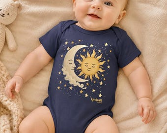 Puede incluir: Body de bebé azul marino con un diseño celestial que presenta un sol, una luna y estrellas sonrientes. El body tiene mangas cortas y cierre de broche. El texto "lyrecraft" está impreso en la parte inferior derecha.
