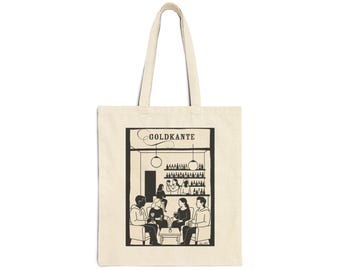 Puede incluir: Bolso tote beige con una ilustración en blanco y negro de una escena de bar. La ilustración presenta a personas sentadas en mesas, una barra con botellas y la palabra "GOLDKANTE" encima de la barra.