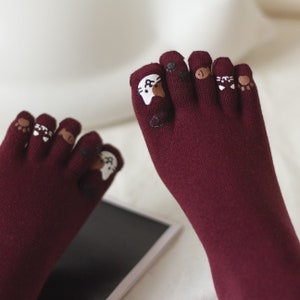 Peut inclure: Chaussettes de pieds bordeaux avec des motifs d'animaux mignons. Les chaussettes ont un motif de chat, d'ours et d'empreinte de patte.