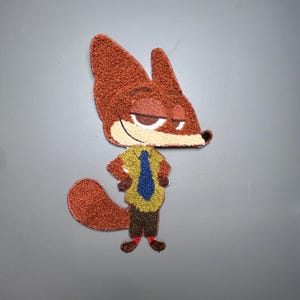 May include: Embroidered patch featuring a cartoon fox character with a sly expression. The fox has brown fur, a yellow shirt, a blue tie, and brown pants. The patch is likely for clothing or accessories.