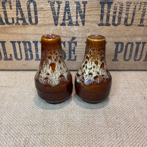 May include: A pair of brown and white salt and pepper shakers with a speckled glaze.