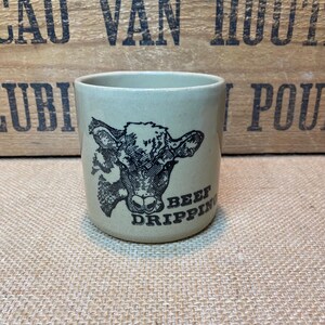 May include: A ceramic mug featuring a black and white illustration of a cow's head and the text "Beef Dripping".