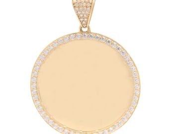 May include: A circular gold pendant featuring a smooth, polished gold center disc framed by a border of small, clear, sparkling stones. The triangular bail at the top is also encrusted with matching clear stones, creating a cohesive look.