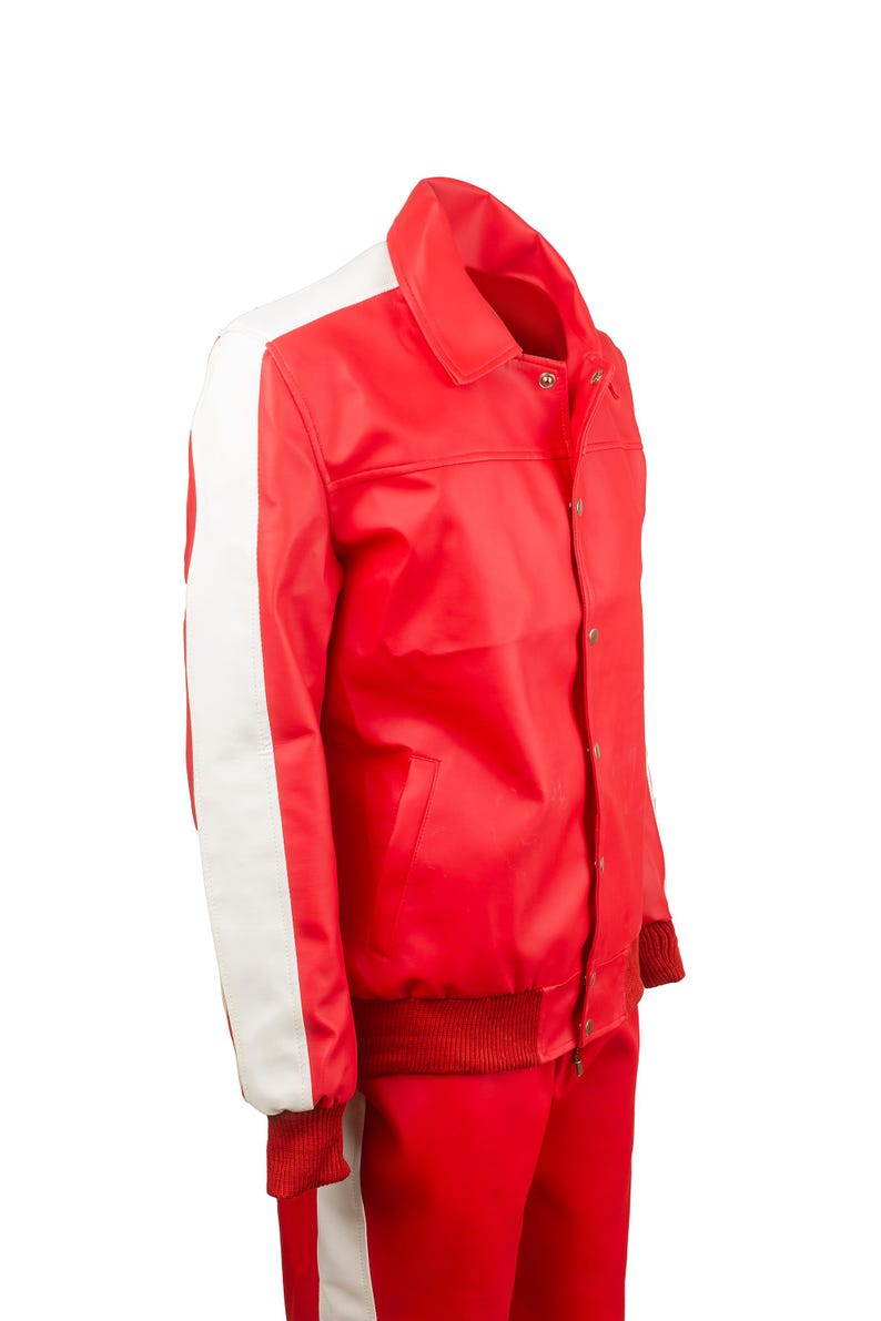 May include: Red jacket with white stripes on the sleeves. The jacket has a collared neckline, a button-up front, and ribbed cuffs and hem. The matching red pants have a white stripe down the side. The outfit is made of a shiny material.