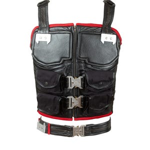 Könnte beinhalten: Schwarze taktische Weste mit roter Paspelierung und mehreren Taschen. Die Weste hat einen Frontreißverschluss, verstellbare Träger und Metallschnallen. Die Weste ist auf Funktionalität und Schutz ausgelegt.