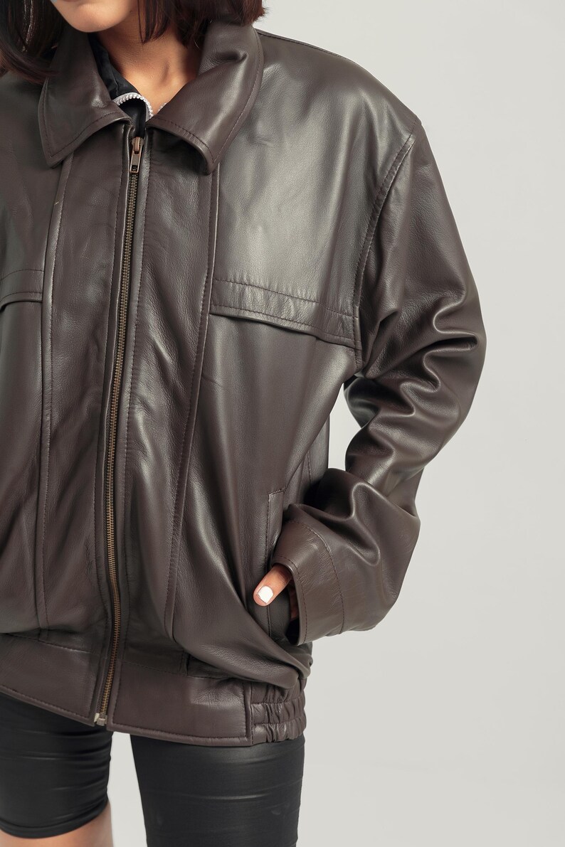 May include: A brown leather bomber jacket with a zipper closure and a ribbed waistband.