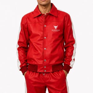May include: Red leather jacket and matching pants with white stripes. The jacket has white accents on the sleeves and the text "OX AND BULLS" with a bull logo. The outfit is a two-piece set.