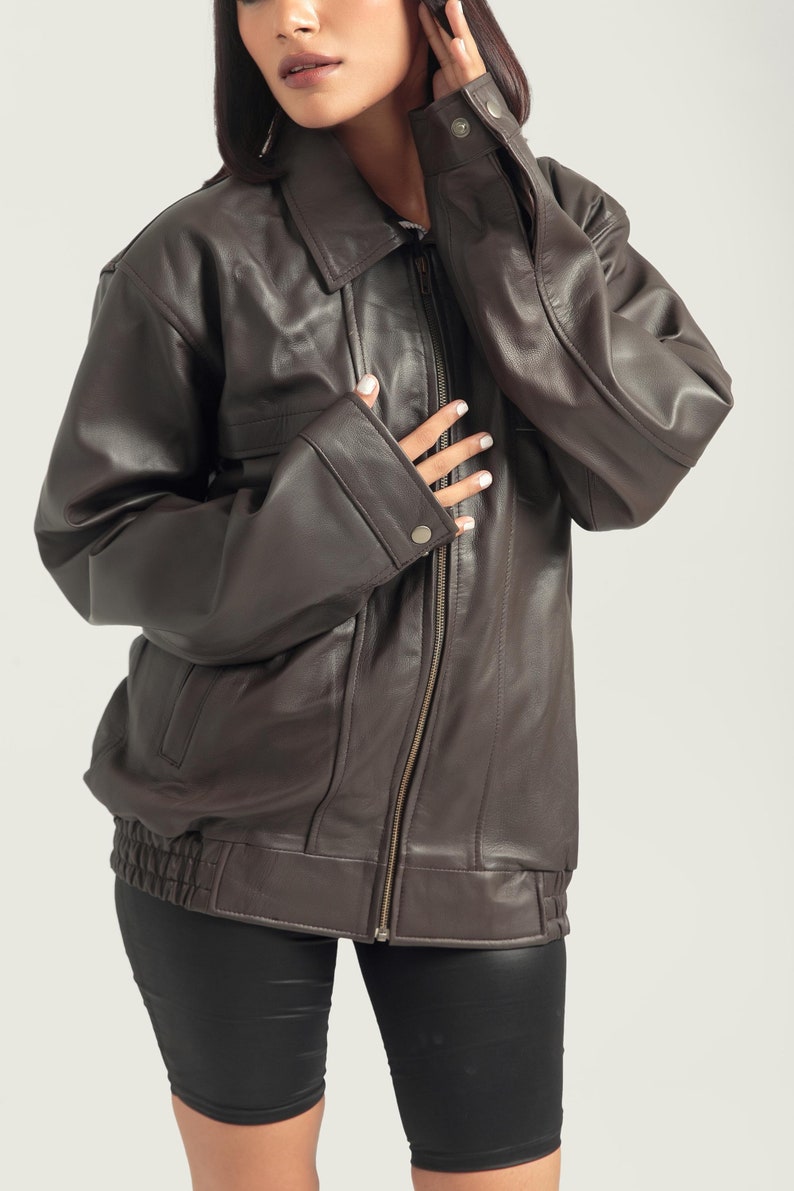 May include: A brown leather bomber jacket with a zipper closure and a ribbed waistband.