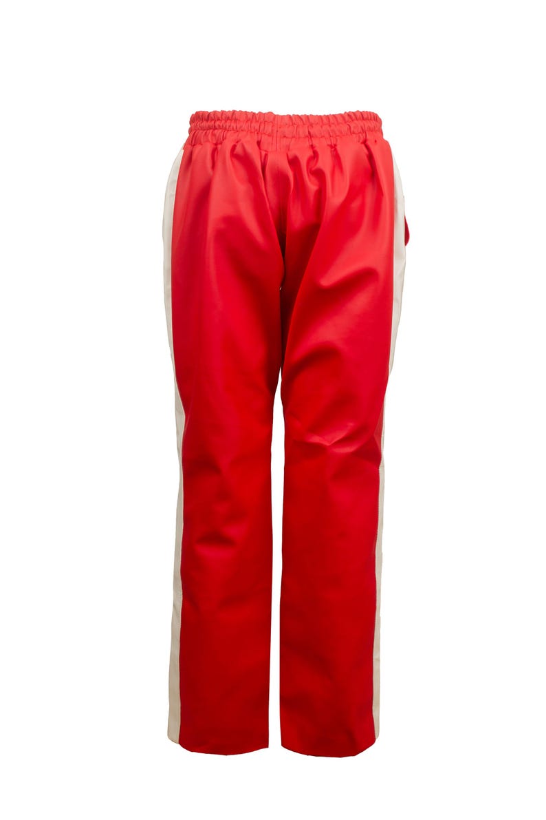 May include: Red athletic pants with a white stripe down the side. The pants have an elastic waistband. The material has a slight sheen. These pants are suitable for sports or casual wear.
