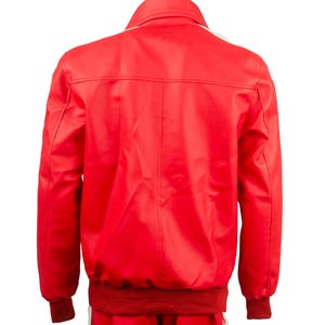 May include: Red track suit with white stripes on the sleeves and legs. The jacket has a ribbed collar and cuffs. The back of the jacket is visible, showing the seams and the white stripe detail.