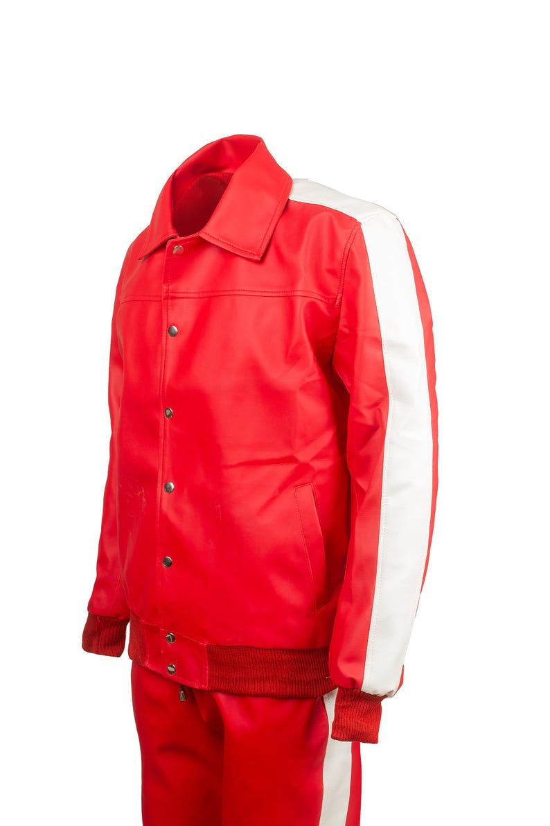 May include: A red jacket with a white stripe down the sleeve. The jacket has a collar, snap closures, and red ribbed cuffs and hem. The matching red pants have a white stripe down the side.