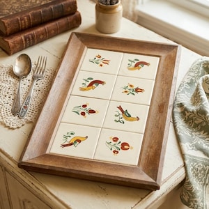 May include: A rectangular wooden serving tray featuring eight inset ceramic tiles. Each tile displays a hand-painted motif of a colorful bird or a floral arrangement in shades of red, yellow, and green against an off-white background.