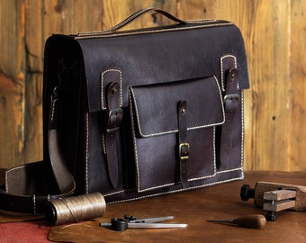 May include: A brown leather satchel with a flap closure, two buckles, and a front pocket. The bag has white stitching and a strap.