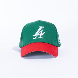 May include: Green and red baseball cap with a white logo on the front. The cap has a curved brim and a structured crown. The logo appears to be a stylized number 4 and the letter A. The cap is likely made of a durable fabric.
