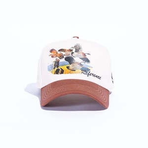 May include: A baseball cap with a brown brim and a white crown. The cap features a colorful illustration of birds in flight over a field. The word "Reference" is printed on the side.