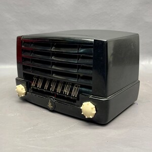 May include: A black vintage radio with a white dial and knobs. The radio has a grill on the front and a tuning dial with numbers from 55 to 160.