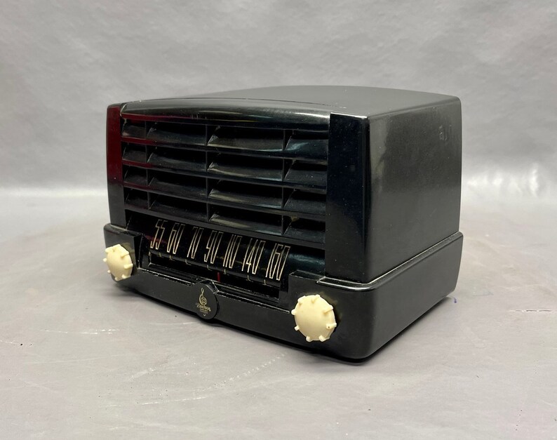 May include: A black vintage radio with a white dial and knobs. The radio has a grill on the front and a tuning dial with numbers from 55 to 160.