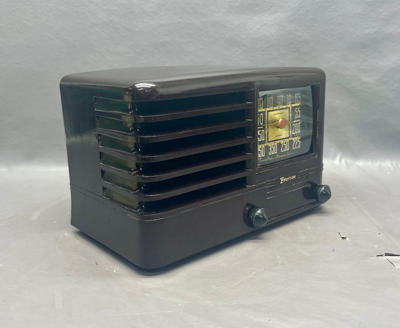 K&ouml;nnte beinhalten: Ein Vintage-Radio der Marke Zenith mit einem schwarzen Kunststoffgeh&auml;use und einem goldenen Zifferblatt. Das Radio hat ein Lautsprechergitter an der Vorderseite und zwei Kn&ouml;pfe auf der rechten Seite.