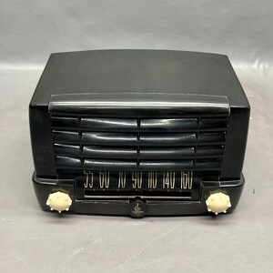 May include: A black vintage radio with a white dial and knobs. The dial has numbers from 55 to 160.