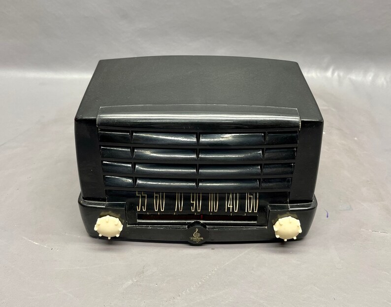 May include: A black vintage radio with a white dial and knobs. The dial has numbers from 55 to 160.