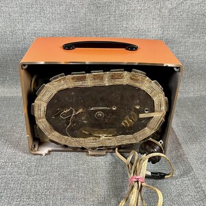 Puede incluir: Radio vintage naranja y marr&oacute;n con asa negra. Los componentes internos de la radio son visibles, incluido un gran altavoz ovalado y cableado. Se adjunta un cable de alimentaci&oacute;n con enchufe.