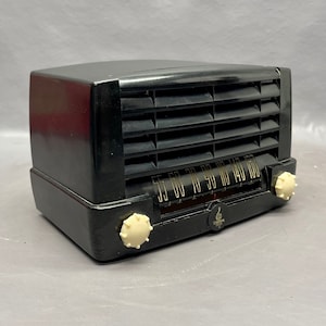 May include: A black vintage radio with a white dial and knobs. The radio has a grill on the front and the text "55 60 70 80 90 110 140 160" on the dial.