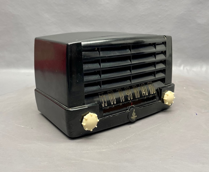 May include: A black vintage radio with a white dial and knobs. The radio has a grill on the front and the text "55 60 70 80 90 110 140 160" on the dial.