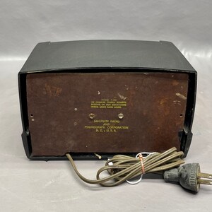 May include: Black and brown vintage Emerson Radio and Phonograph Corporation record player with a power cord and plug.