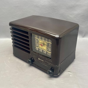 K&ouml;nnte beinhalten: Ein braunes Vintage-Radio von Emerson mit einem Zifferblatt, das von 130 bis 65, von 150 bis 55, von 550 bis 200, von 450 bis 225, von 350 bis 250 reicht. Das Radio hat zwei Kn&ouml;pfe an der Vorderseite.