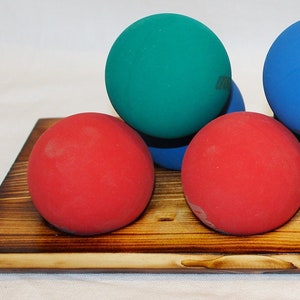 May include: A wooden board with seven colorful balls, including red, blue, and green. The balls are arranged in a row on the board.