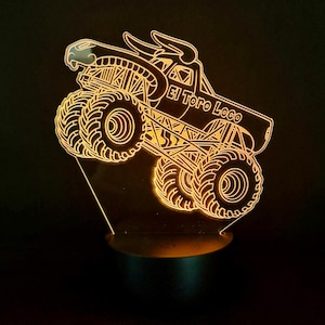 May include: An illuminated LED night light with a monster truck design. The truck is outlined in a warm yellow light, with the words "El Toro Loco" visible. The light sits on a small, round base.