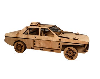 Könnte beinhalten: Ein Holzmodellauto im Taxidesign. Das Modell ist aus hellbraunem Holz gefertigt und weist detaillierte Ausschnitte für Fenster, Türen und Räder auf. Es verfügt über ein Dachlicht und aufwendige Raddesigns.