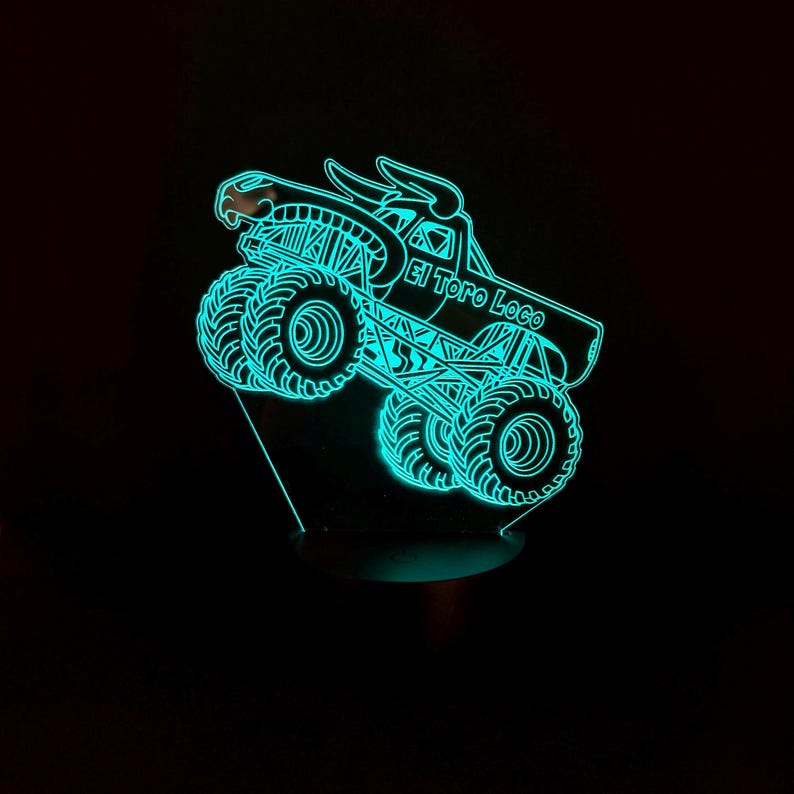May include: A neon blue LED light featuring a monster truck design. The truck is labeled "El Toro Loco" and has large tires and a bull head on top. The light is on a black base and emits a bright glow.