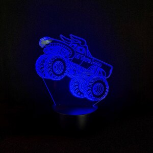 May include: A blue LED night light shaped like a monster truck with the text "El Toro Loco". The truck has large tires and a bull head design. The light is on a black base and emits a bright blue glow.