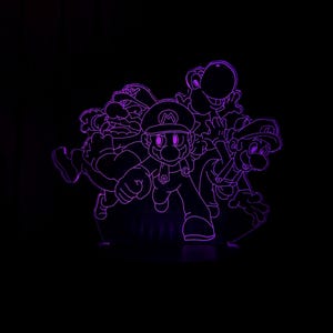 Puede incluir: Una luz LED p&uacute;rpura con personajes de la franquicia de videojuegos Super Mario. Los personajes incluyen a Mario, Luigi, Wario y Yoshi, sobre un fondo negro.
