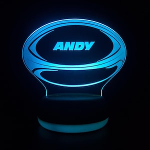 May include: A blue LED night light shaped like a rugby ball with the name "ANDY" inscribed on it.
