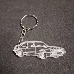 May include: A clear acrylic keychain featuring a detailed outline of a classic Ford car. The keychain is attached to a silver metal chain with a circular ring.
