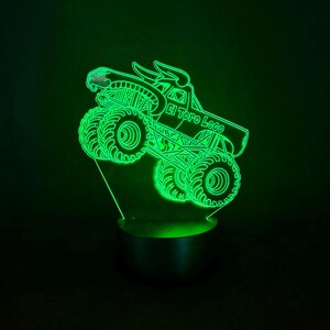 May include: A neon green LED night light featuring a monster truck design. The truck has large tires and the text "El Toro Loco" on the side. The light is on a black base and emits a bright green glow.