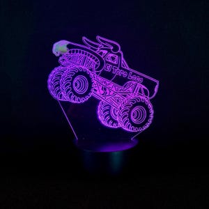 May include: A purple LED night light featuring a monster truck design. The truck has large tires, a bull head, and the text "El Toro Loco". The light is on a black base and emits a purple glow.
